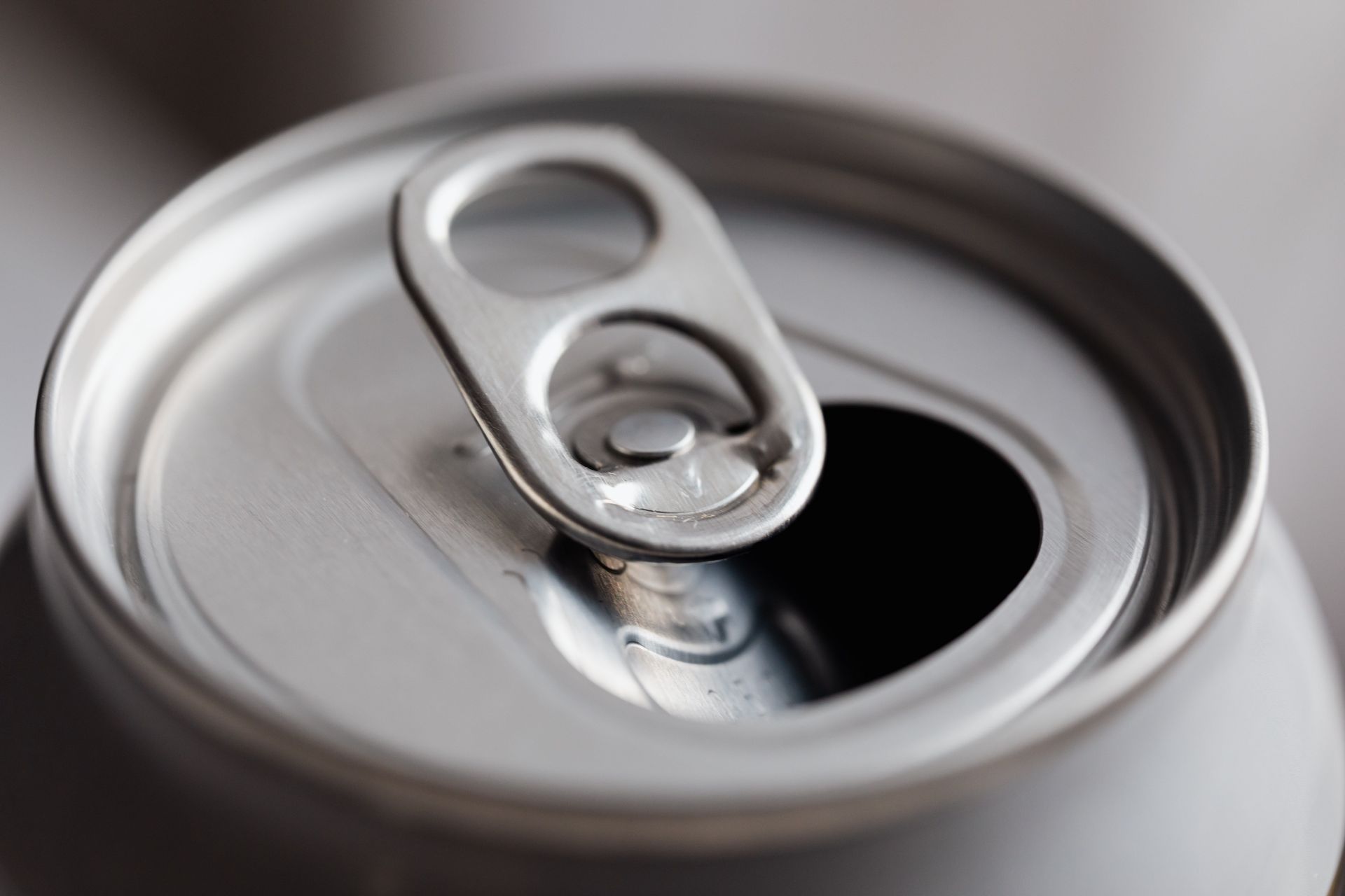 From above closeup of open wide mouth aluminum soft drink can on grey background